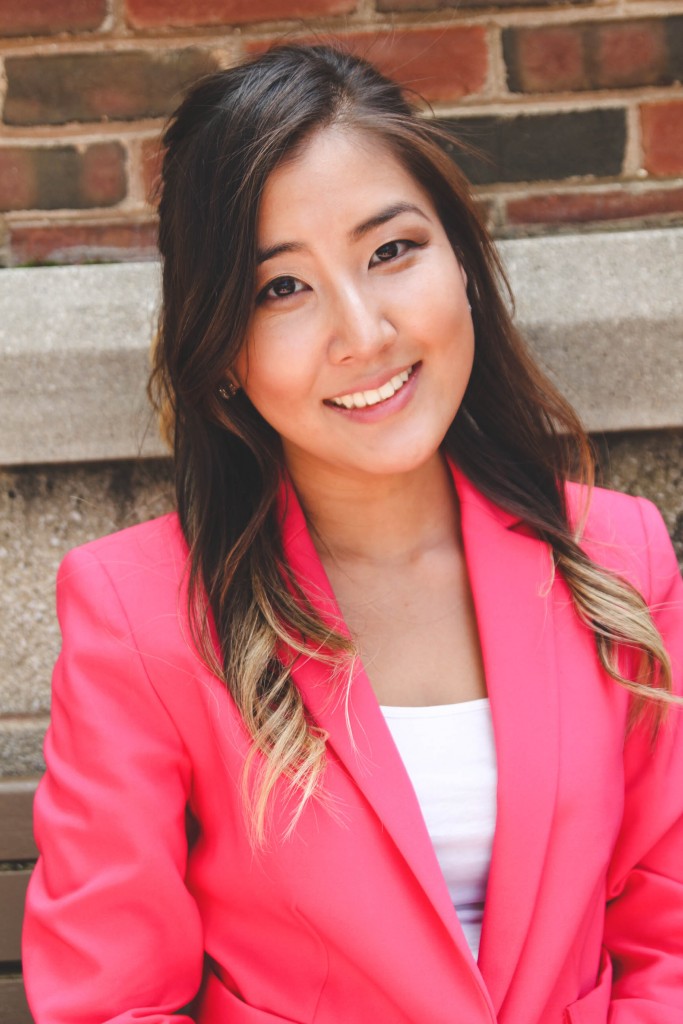 Woman with dark hair smiling wearing a pink suit