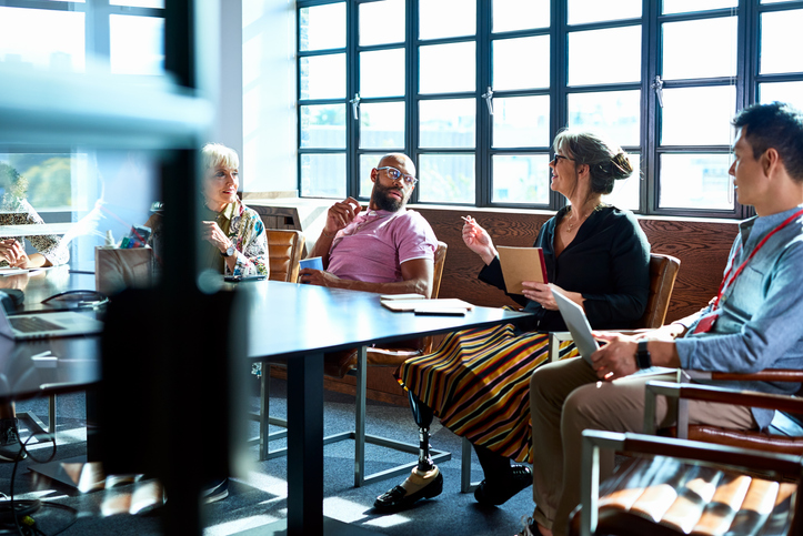 Senior female businesswoman with prosthetic leg working with multi racial coworkers in business strategy review, leadership, knowledge, admiration