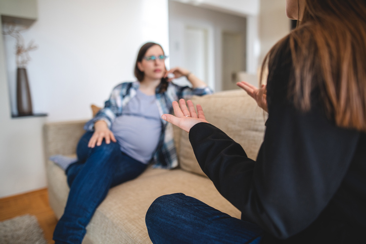 Deaf woman gesturing sign language to her pregnant friend Two good loving friends discussing modern issues in the deafness society using sign language.