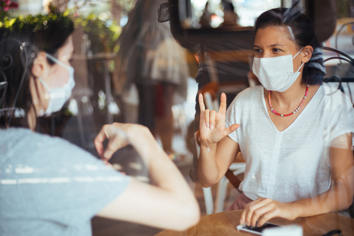 Two young woman with mask speak in sign language Two young woman with mask speak in sign language