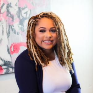 Woman with brown and blond locs smiling at camera