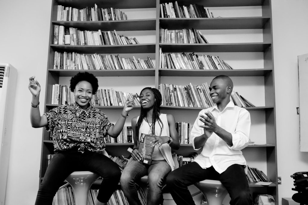 Three women sitting in chair clapping in black anad white