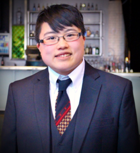 [Photo: Lydia Brown, a young East Asian person wearing navy blue suit and retro-patterned necktie, smiling after their talk for the Colorado Trust's Health Equity Learning Series. Photo by Rachel Mondragon, February 2017, Denver, Colorado.]