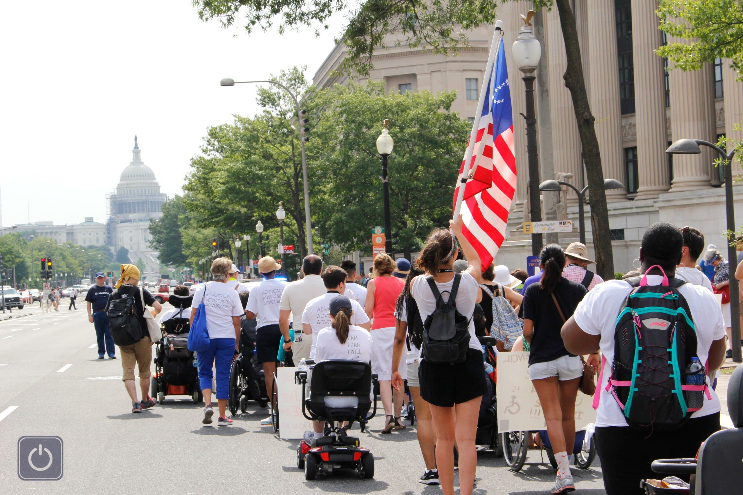 group of activists marching down the street towards the white house. One person holds an American flag.