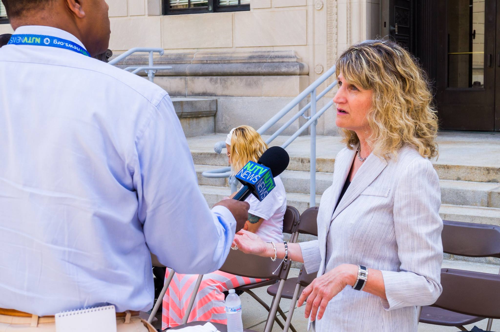 Woman giving a media interview next to a man holding a microphone