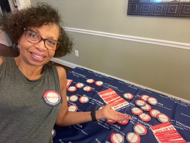 Black woman wearing "I voted" sticker sitting in front of table full of Swag