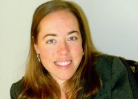 Robyn Powell headshot. woman smiling with long hair in black shirt