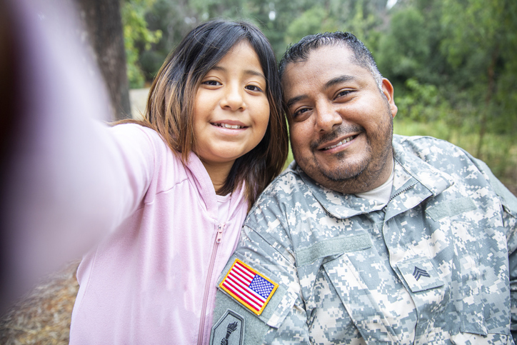 A uniformed veteran takes a photo with his daughter