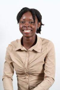 Headshot of Audrey Agbefe, a dark skin black girl with hair pulled up. She is wearing a tan button down shirt.