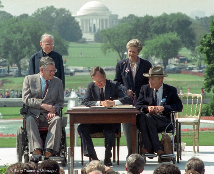 President George H.W. Bush signs the Americans with Disabilities Act on July 26, 1990, at the White House. Joining him are Evan Kemp, of the Equal Opportunity Employment Commission; the Reverend Harold Wilke; Sandra Parrino, of the National Council on Disability; and Justin Dart, of the President’s