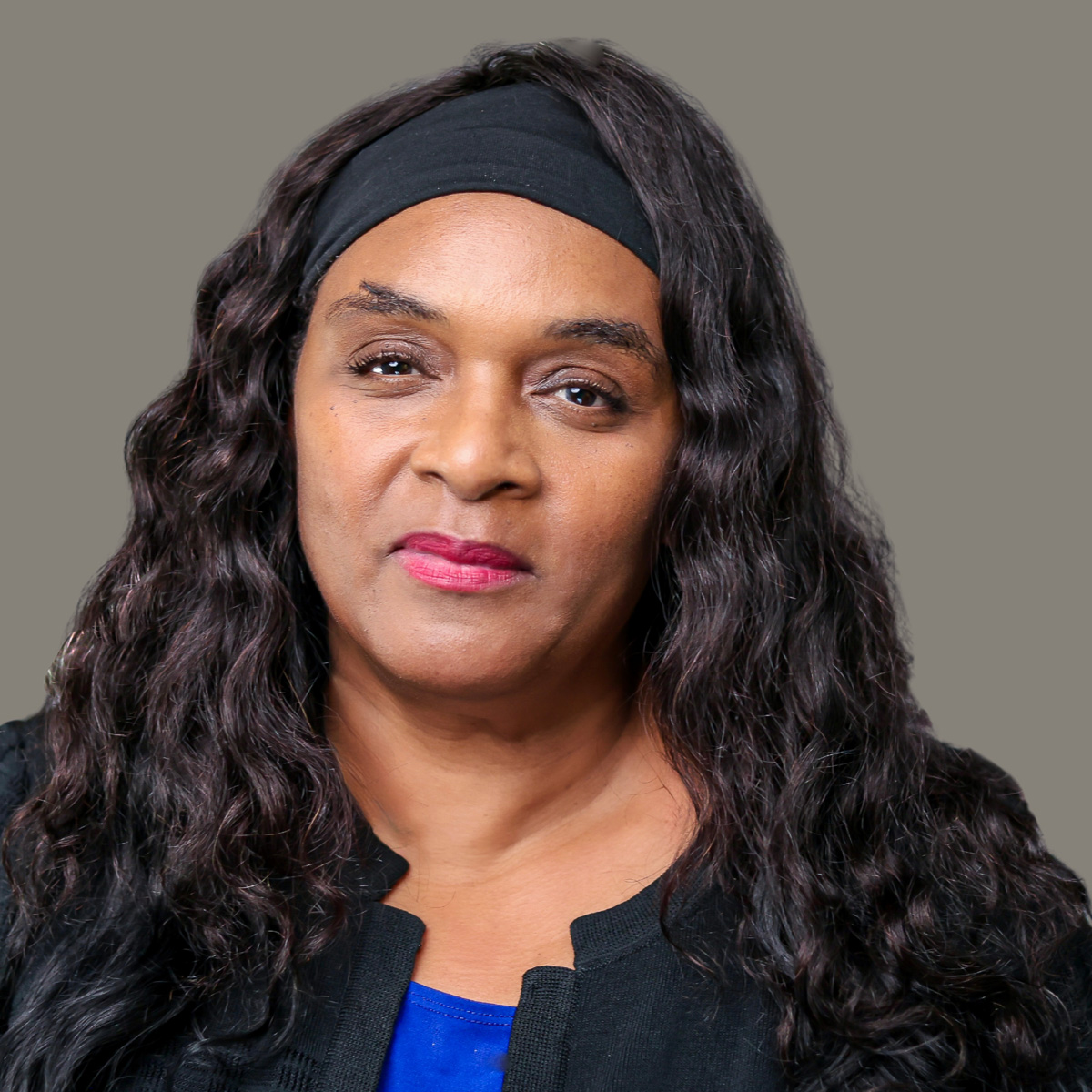A full headshot of Cheri wearing a black headband, black jacket, and blue shirt.
