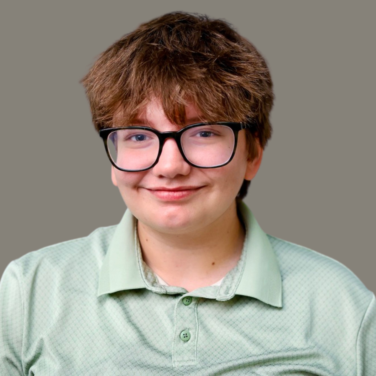 Studio headshot of Miri with short, layered brown hair, bangs, and black thick-framed glasses. He is facing forward with a closed-mouth smile, wearing a light sage-green collared polo shirt against a solid, neutral grey background.